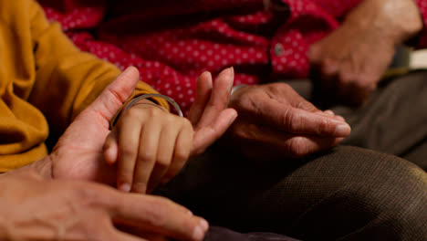 Close-Up-Of-Multi-Generation-Male-Sikh-Family-Wearing-And-Discussing-Traditional-Silver-Bangles-Or-Bracelets-Sitting-On-Sofa-At-Home-2